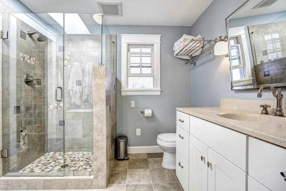 Salle de bain moderne rénovée avec douche à l'italienne, carrelage en pierre naturelle, parois de verre trempé