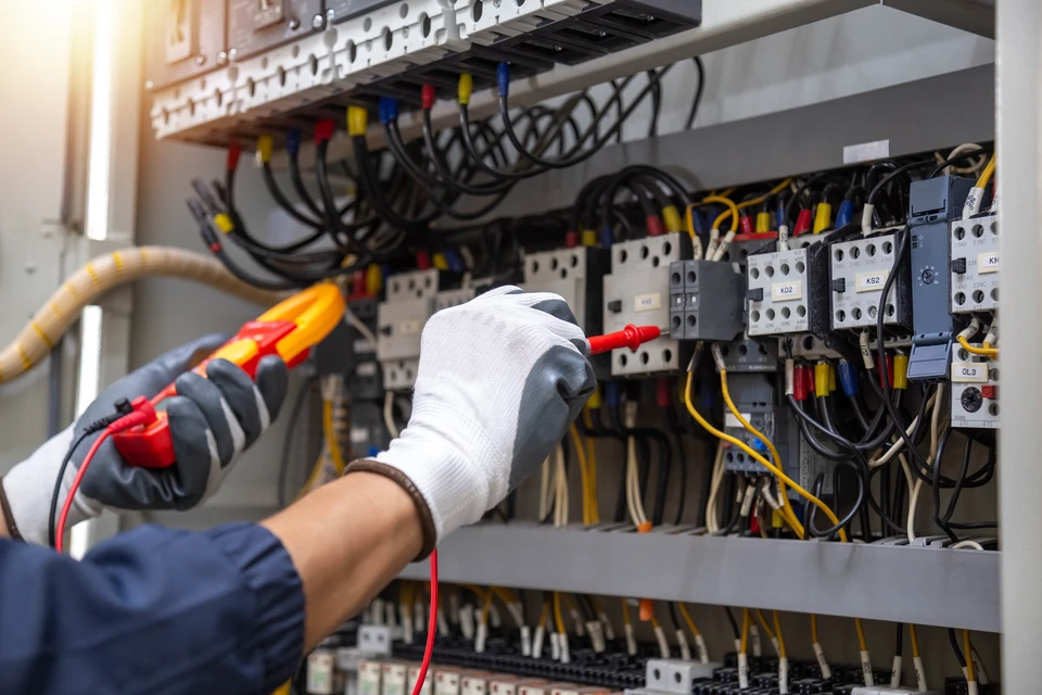 En vérifiant le système électrique, un électricien utilise un compteur électrique pour vérifier le système électrique au niveau d'une armoire de commande