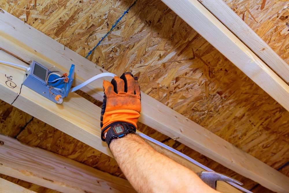 Un électricien installe des lampes de plafond encastrées à DEL dans une nouvelle maison