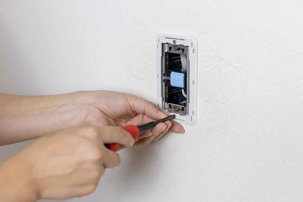 Un électricien installe un nouvel interrupteur d'éclairage